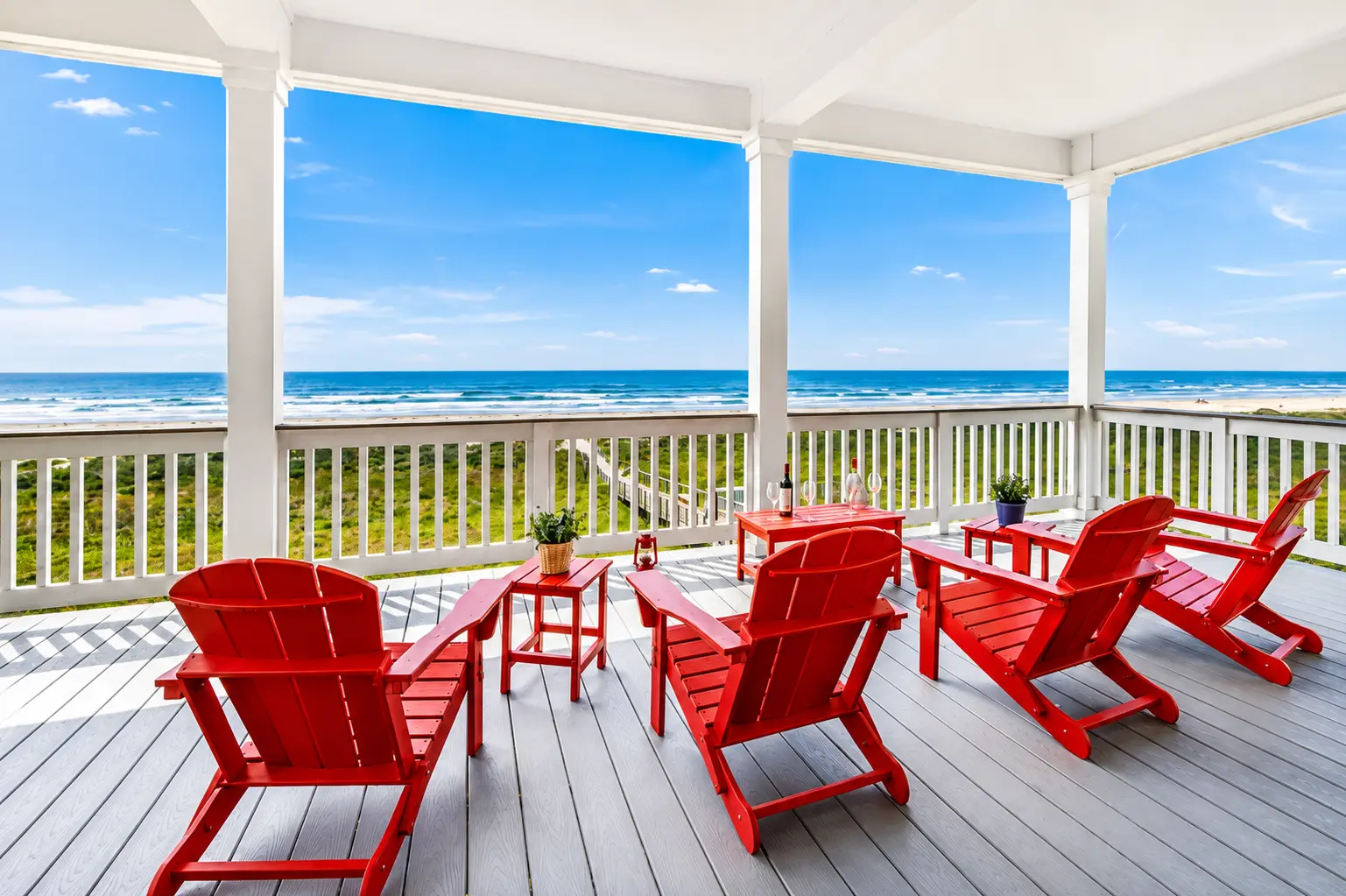 Ground-level patio with red seating near beach access